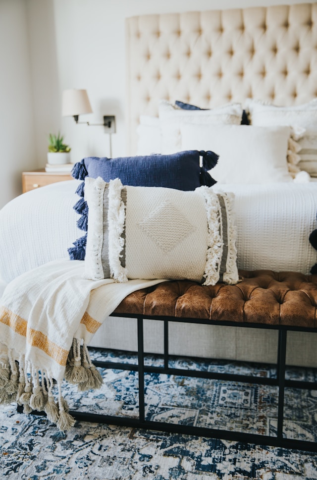 cushions and a throw on a bench in front of a bed
