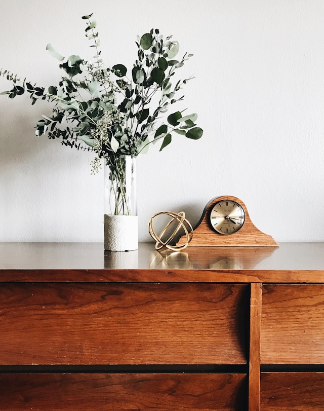 vase with fake plant on a dresser with other decorative elements